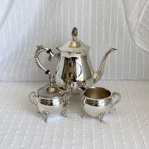 Könnte beinhalten: Ein Set aus drei Keramikbechern mit gesprenkelter, matter Oberfläche. Die Becher sind in den Farbtönen Creme, Hellgrau und Dunkelgrau gehalten. Jeder Becher hat ein schlichtes, minimalistisches Design, ideal für Kaffee oder Tee.