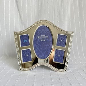 May include: Silver-toned multi-photo frame with an oval center and four smaller square openings. The frame has a decorative edge and a blue patterned background. The text "Sweet Memories" is visible.