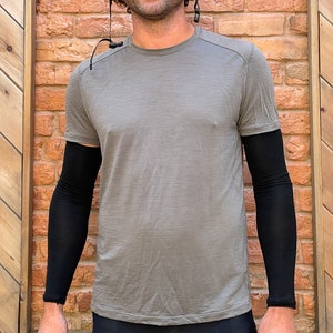 May include: A person wearing a gray t-shirt with black arm warmers.