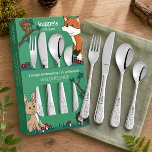 Könnte beinhalten: Ein vierteiliges Kinderbesteck aus Edelstahl bestehend aus Gabel, Messer, Löffel und kleinem Löffel. Jeder Griff ist mit dem Namen Leonie und einer kleinen Tiergravur versehen. Das Set wird neben der grünen Verpackung präsentiert.