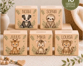Könnte beinhalten: Fünf quadratische Spardosen aus hellem Holz mit Münzschlitz auf der Oberseite. Jede Box zeigt eine einzigartige Tierillustration, darunter einen Dachs, ein Faultier, eine Giraffe, ein Zebra und einen Leoparden, sowie die Namen Noah, Sophia, Julius, Mika und Louisa.