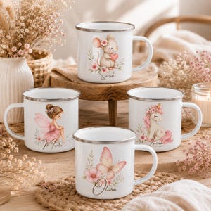 Könnte beinhalten: Vier weiße Tassen im Emaille-Stil mit silbernen Rändern, jede mit einer individuellen Illustration und einem Namen versehen. Die Motive zeigen eine Maus mit Herz, eine Fee mit rosa Flügeln, ein Einhorn und einen Schmetterling mit rosa Blüten.