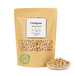 May include: A kraft paper bag of chickpeas with a clear window, a small glass bowl of chickpeas, and a label that reads "Chickpeas (Garbanzo Beans) A Mountain Herbs 100% Natural."