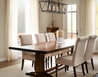 Könnte beinhalten: Ein Esszimmer-Set mit einem großen, rechteckigen Holztisch mit dunklem Finish, umgeben von sechs gepolsterten Stühlen. Über dem Tisch hängt ein schwarzer geometrischer Kronleuchter. Der Raum hat neutrale Töne und natürliches Licht.