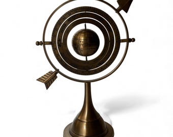 May include: A bronze-colored armillary sphere with a globe at its center. The sphere has multiple rings with markings and two arrow-shaped pointers. It stands on a pedestal base, showcasing a vintage, decorative design.