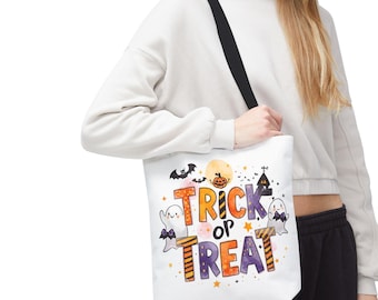 May include: White tote bag with a black strap. The bag displays a colourful Halloween design with the words "Trick or Treat", ghosts, bats, a pumpkin, and a haunted house.