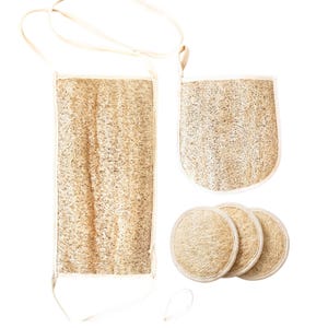 Può includere: Un set da bagno in luffa naturale, composto da un lungo scrub per la schiena rettangolare, un guanto e tre dischetti per il viso rotondi. Il set è realizzato in materiale di luffa beige strutturato con finiture bianche e anelli per appenderlo.