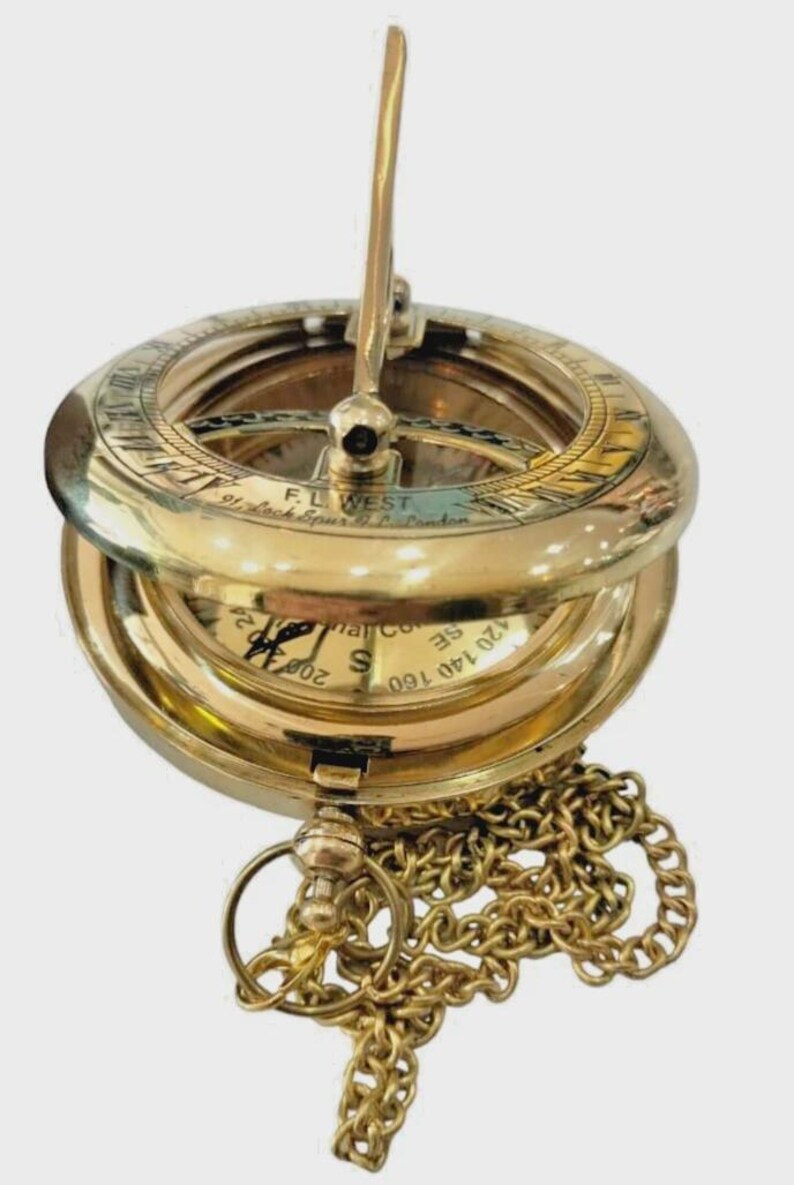 Puede incluir: Una br&uacute;jula de reloj de sol de lat&oacute;n vintage con tapa con bisagras y cadena. La br&uacute;jula presenta marcas grabadas y un gnomon. El instrumento se utiliza para determinar la hora del d&iacute;a.