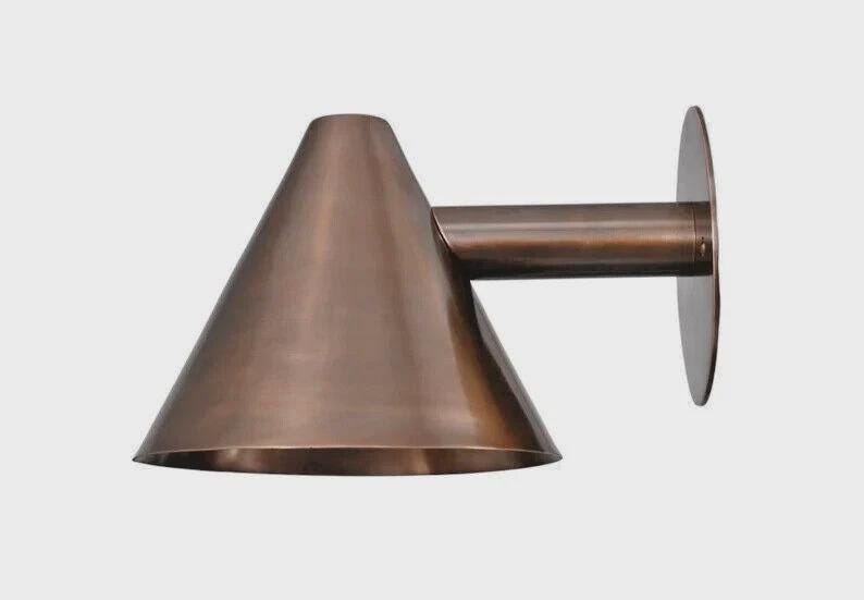 May include: A copper-colored wall sconce with a conical shade and a cylindrical arm extending to a circular mounting plate. The fixture has a modern, minimalist design and is made of metal.