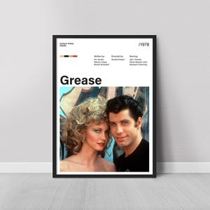 Può includere: Un poster incorniciato del film "Grease" con bordo nero. Il poster include una foto dei due attori principali, il titolo del film e l'anno 1978. Il poster è esposto contro un muro bianco.