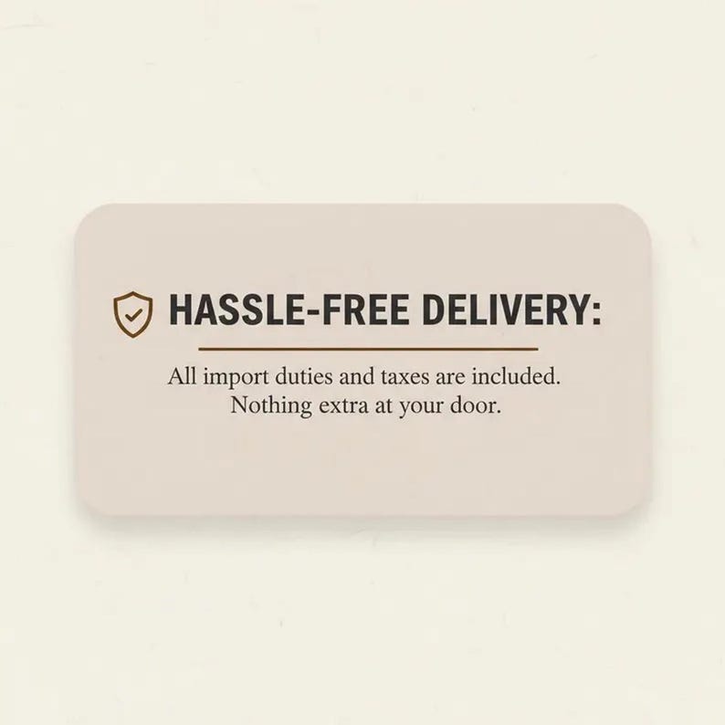 May include: A rectangular beige information card with rounded corners featuring a brown shield icon with a checkmark. The text reads: HASSLE-FREE DELIVERY: All import duties and taxes are included. Nothing extra at your door.