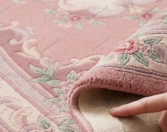 May include: A pink area rug featuring a floral pattern with light pink, cream, and sage green accents. The rug has a thick, tufted pile surface and a woven beige backing visible where the corner is folded over to reveal the construction details.