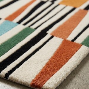 May include: A rectangular area rug featuring a textured, tufted surface with a geometric pattern of black, white, orange, green, and light blue blocks and stripes. The design consists of varied rectangular shapes arranged in a repeating layout.