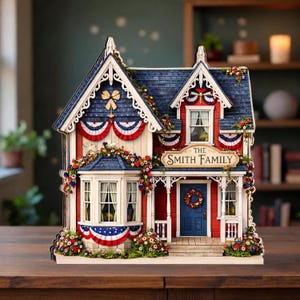 May include: A decorative miniature house with red, white, and blue patriotic bunting and floral accents. The house features a blue roof, a red exterior, and a sign that reads "The Smith Family".