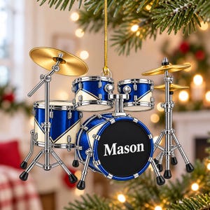 Può includere: Un ornamento a forma di batteria in miniatura con finitura blu e crema, componenti in metallo argentato e piatti dorati. La grancassa è nera con il nome Mason stampato in bianco. Il set è appeso tramite un cordino dorato.