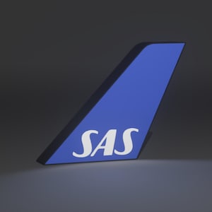 May include: A blue and black illuminated sign featuring the SAS logo. The sign is shaped like an airplane tail fin, with the letters "SAS" in white. The background is a dark grey.