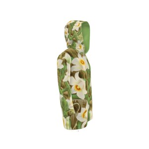 Puede incluir: Una sudadera con capucha con un estampado floral de narcisos blancos con centros amarillos y tallos y hojas verdes. El interior de la capucha es de color verde liso. El fondo es blanco.