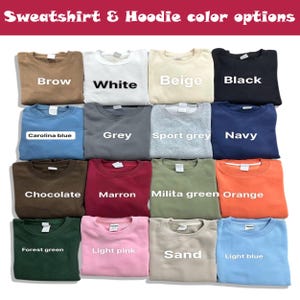 May include: A selection of sweatshirts in a variety of colours, such as brown, white, beige, and black. Other colours include Carolina blue, grey, sport grey, navy, chocolate, maroon, milita green, orange, forest green, light pink, sand, and light blue. Text at the top reads "Sweatshirt & Hoodie color options."
