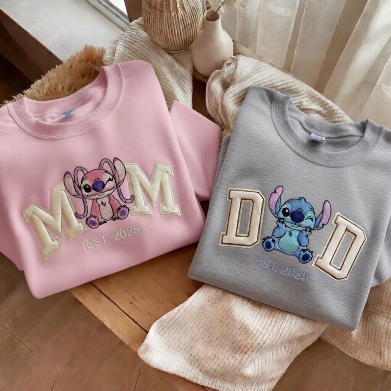 Puede incluir: Dos sudaderas de cuello redondo, una rosa y otra gris. La sudadera rosa tiene la palabra "MOM" con un personaje de dibujos animados y "EST. 2025". La sudadera gris tiene la palabra "DAD" con un personaje de dibujos animados y "EST. 2025".