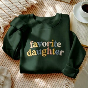 May include: A set of three ceramic mugs with a speckled, matte finish. The mugs are in cream, light grey, and dark grey. Each mug has a simple, minimalist design, ideal for coffee or tea.