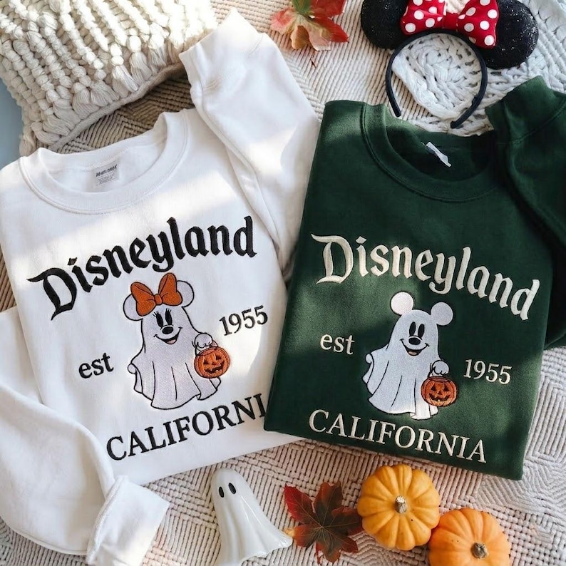 May include: A white sweatshirt and a dark green sweatshirt, both featuring embroidered text reading Disneyland est 1955 California and a graphic of a ghost wearing mouse ears and holding a jack-o'-lantern pumpkin bucket.