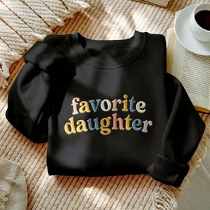 May include: A set of three ceramic mugs with a speckled, matte finish. The mugs are in cream, light grey, and dark grey. Each mug has a simple, minimalist design, ideal for coffee or tea.