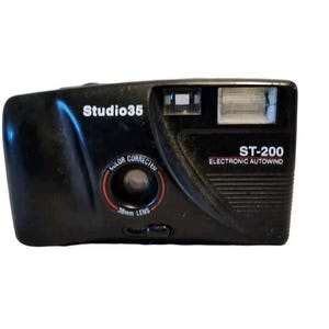 Puede incluir: Una cámara de película negra Studio 35 ST-200 de 35 mm con flash incorporado y avance automático electrónico. La cámara tiene una lente de 38 mm con corrección de color.