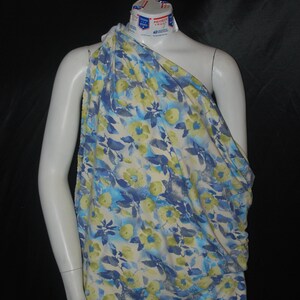 May include: A white fabric with a blue and green floral print. The fabric is draped over a white mannequin.