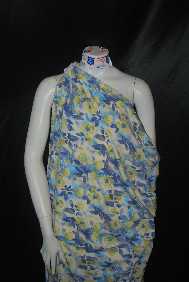 May include: A white fabric with a blue and green floral print. The fabric is draped over a white mannequin.