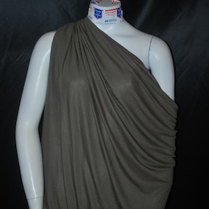 May include: A brown one-shoulder draped top made of a soft, flowing fabric. The top is gathered at the shoulder and drapes loosely over the body.