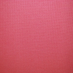 May include: A close-up of a textured, pink fabric. The fabric has a subtle sheen and a fine weave.
