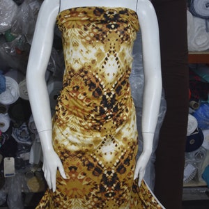 May include: A brown and white patterned fabric with a geometric design. The fabric is draped over a white mannequin.