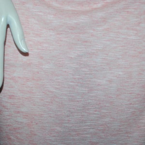 May include: A close-up of a pink and white textured fabric. The fabric has a subtle horizontal stripe pattern.