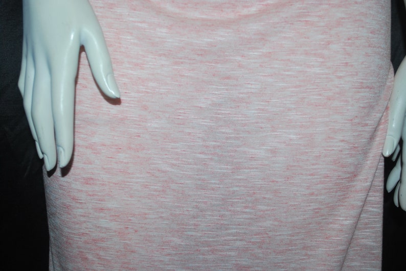 May include: A close-up of a pink and white textured fabric. The fabric has a subtle horizontal stripe pattern.