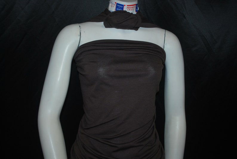 May include: A brown sleeveless top made of a soft, stretchy fabric. The top is fitted and has a cowl neck.