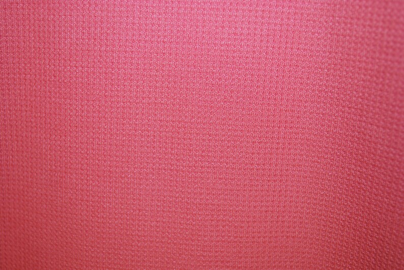 May include: A close-up of a pink fabric with a textured surface.