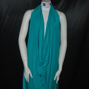 以下が含まれることがあります： 柔らかく伸縮性のあるターコイズブルーの halter top。トップはフロントでドレープされ、ギャザーが寄せられており、ゆったりとした流れるようなシルエットになっています。