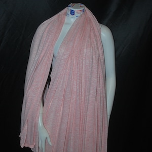 May include: A pink and white striped knit fabric draped over a mannequin. The fabric is soft and stretchy, and would be perfect for making a variety of garments.
