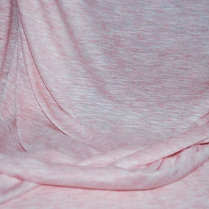 May include: A pink and white textured fabric with a soft, drapey feel. The fabric is wrinkled and folded, creating a natural, organic look.
