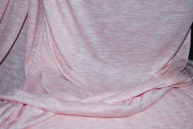 May include: A pink and white textured fabric with a soft, drapey feel. The fabric is wrinkled and folded, creating a natural, organic look.