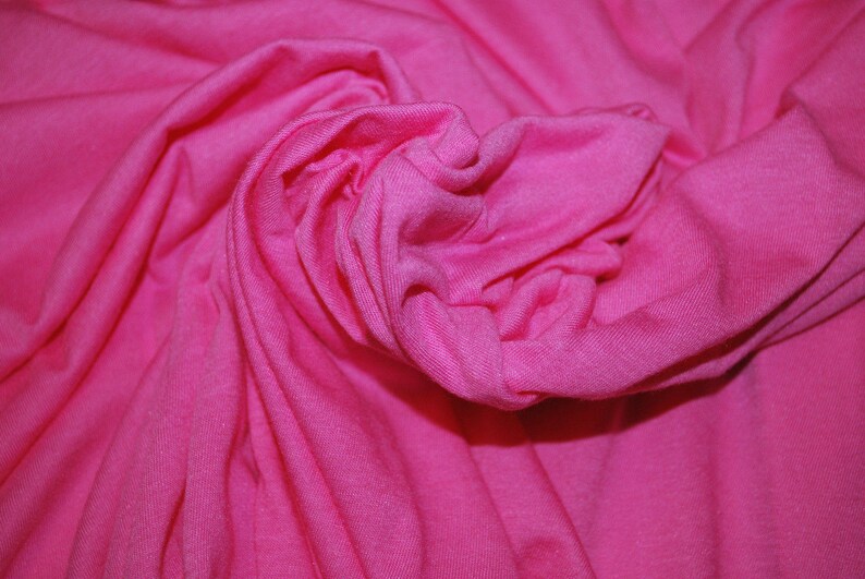 May include: A close-up of a bright pink fabric, showing the texture and folds of the material.