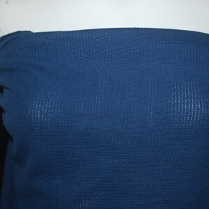 May include: A close-up of a dark blue waffle knit fabric. The fabric has a textured surface and is soft to the touch.