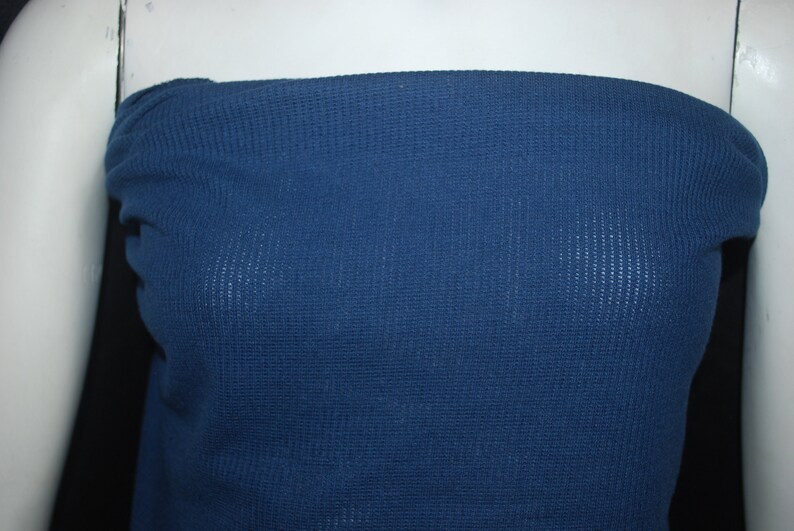 May include: A close-up of a dark blue waffle knit fabric. The fabric has a textured surface and is soft to the touch.