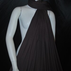 May include: A brown, drapey fabric scarf is draped over a white mannequin. The scarf is made of a soft, lightweight material and has a flowing, elegant look.