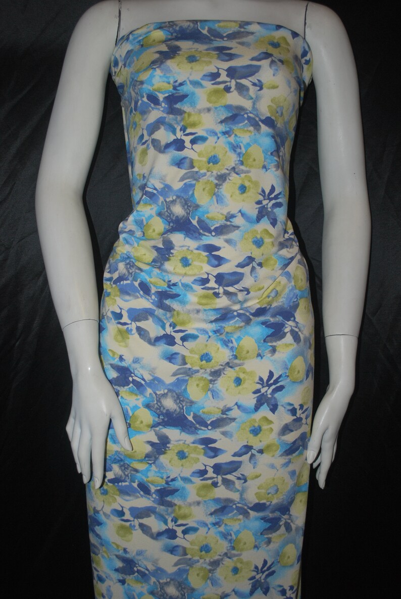 May include: White fabric with a blue and yellow floral print. The fabric has a watercolor effect and features a variety of flower shapes and sizes.