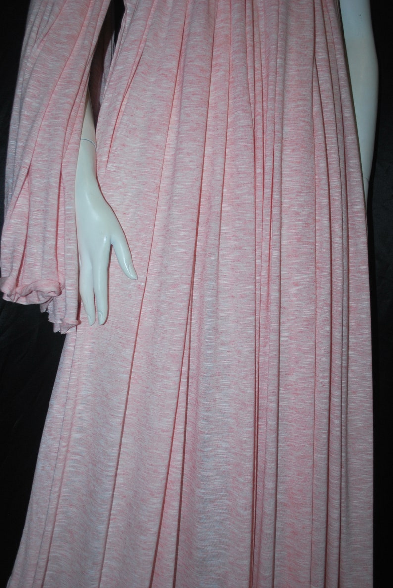 May include: A pink and white striped fabric with a soft, drapey texture. The fabric is pleated and has a subtle sheen.