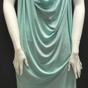 May include: A light blue cowl neck top made of a soft, drapey fabric. The top is sleeveless and has a relaxed fit.
