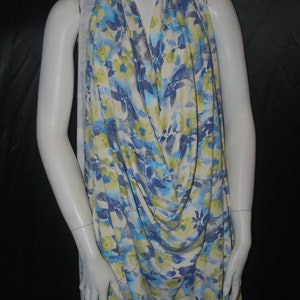 May include: A white fabric with a blue and green floral print. The fabric is draped over a white mannequin.