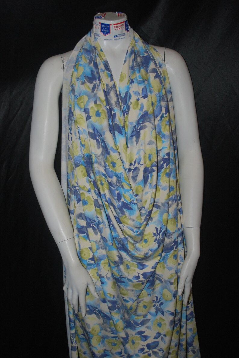 May include: A white fabric with a blue and green floral print. The fabric is draped over a white mannequin.