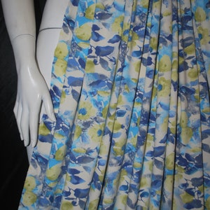 May include: A white fabric with a blue and green floral print. The fabric is pleated and has a soft, watercolor-like design.